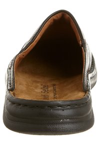Zapato negro tipo slip-on con parte superior de cuero suave, punta redonda, plantilla marrón suave y detalles cosidos a lo largo de los bordes.