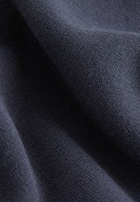Tissu en tricot bleu foncé avec une texture lisse et douce ; présente un motif subtil et uniforme avec de fines coutures partout.