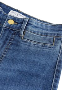 Jeans in denim blu con una finitura sbiadita, caratterizzati da chiusura con bottone dorato e cuciture in contrasto. Etichetta visibile in vita.