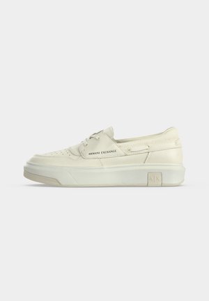 Zapatilla blanca de piel de corte bajo con cordones delanteros, suela gruesa, detalles perforados y marca "Armani Exchange" en el lateral y la suela.