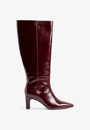 Bota in pelle borgogna al ginocchio con punta affusolata, design elegante e tacco a blocco di 3 pollici. Texture liscia e dettagli di cucitura discreti.