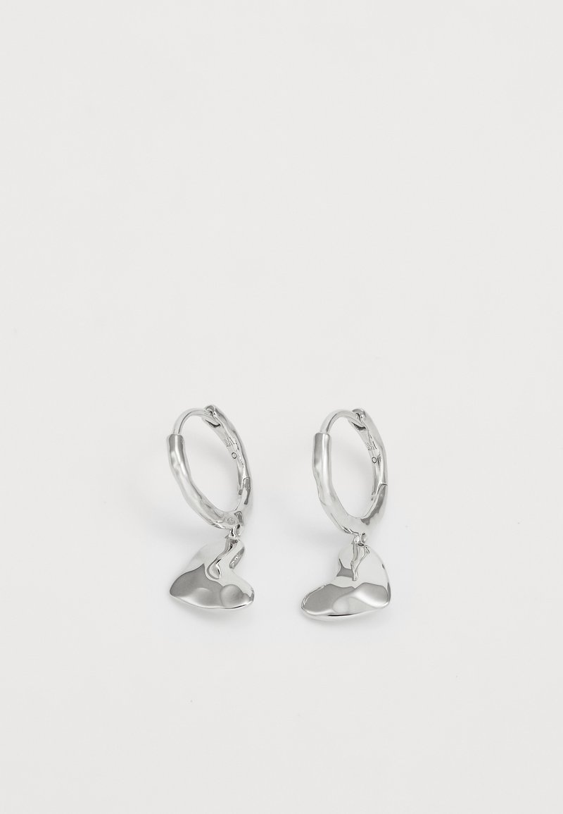 Srebrne naušnice s kružnim oblikom i apstraktnim, glatkim izgledom, obješene sa sjajnim i poliranim završetkom.