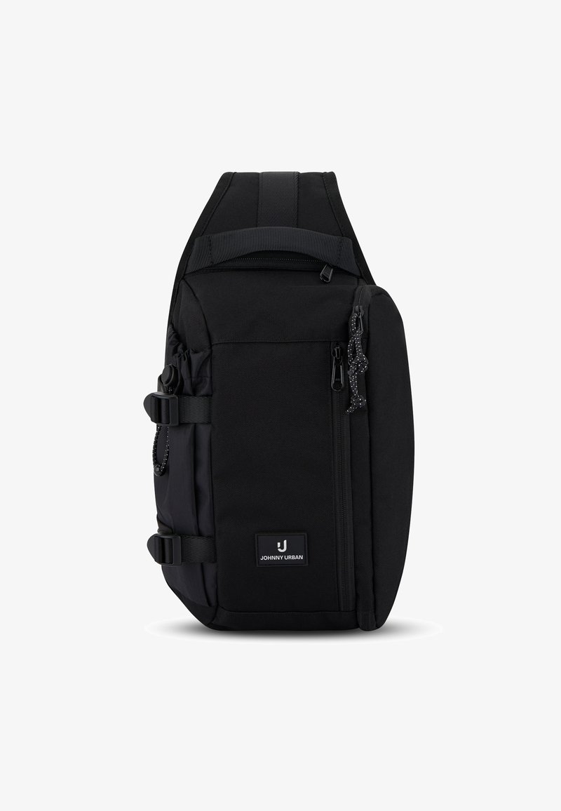 Čierny kompaktný sling batoh s polstrovaným ramenným popruhom, predným vreckom na zips, bočnými prackami a nášivkou s logom Johnny Urban.