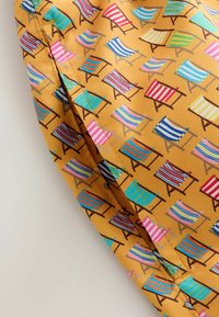 Tissu jaune avec un motif répétitif de petites chaises de plage dans diverses couleurs vives et rayures.