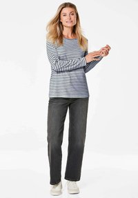 Gestreept grijs-wit langarmshirt van katoen, gecombineerd met donkergrijze jeans en witte sneakers; casual pasvorm en gladde textuur.