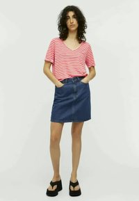 T-shirt à rayures rouges et blanches à manches courtes et décolleté en V, associé à une jupe en denim bleu foncé et des sandales à plateforme noires. Ensemble décontracté.