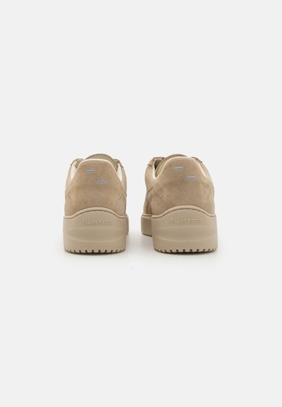 Zapatillas de ante beige con suela gruesa, que presentan un branding minimalista, una textura suave y detalles de costura sutiles en la parte trasera.