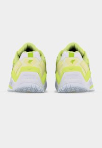 Ζευγάρι αθλητικών παπουτσιών σε νέον κίτρινο και λευκό, εμφανιζόμενα από πίσω, με γκρι ανάγλυφες σόλες, πάνω σε απλό φόντο.