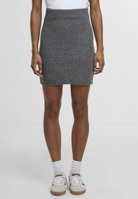 Grå strikket nederdel med ribbet talje, kort længde og blød tekstur, parret med hvide sneakers og ankelstrømper.