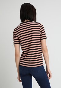 Randig kortärmad t-shirt i rosa och svart, med en rundad halsringning och en figurnära silhuett, tillverkad av mjukt bomullsblandat tyg.