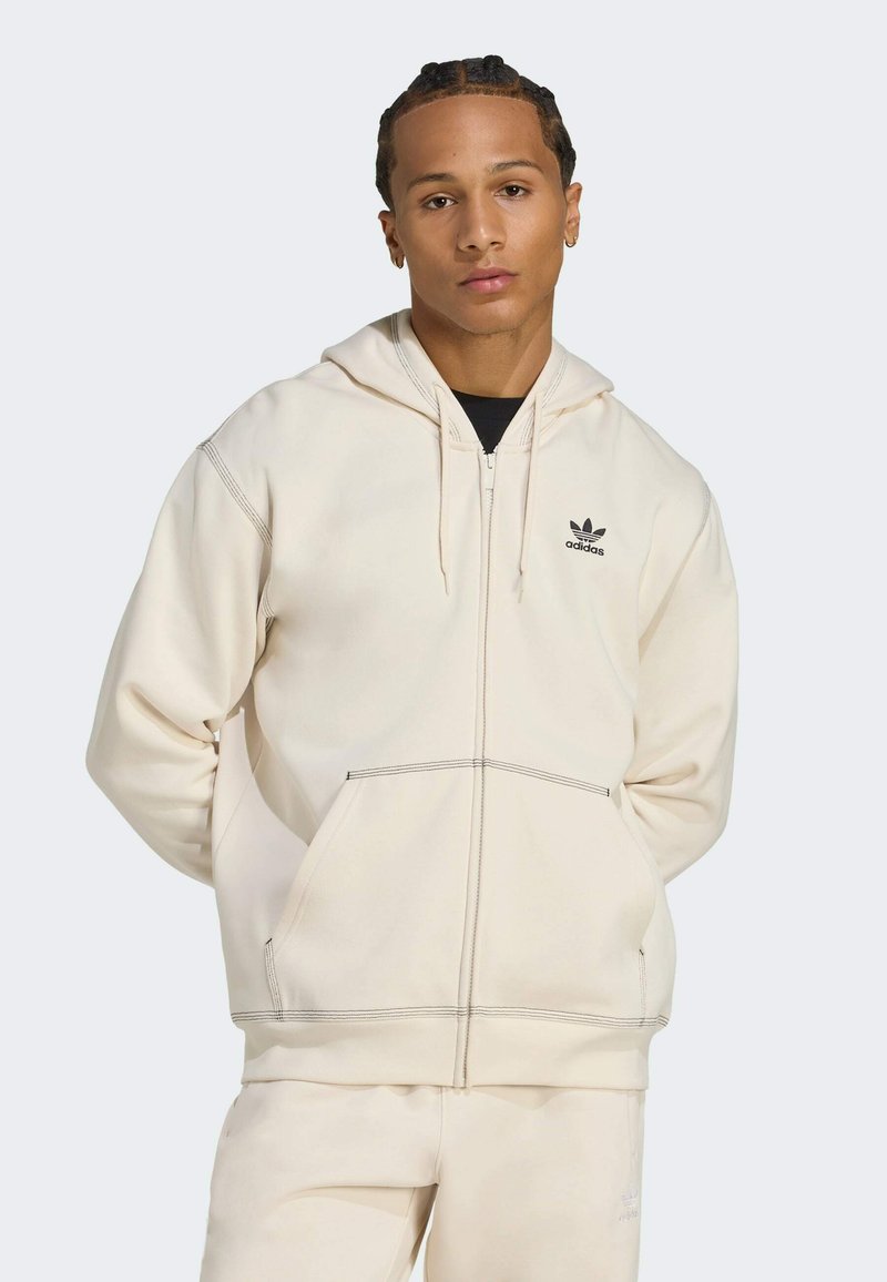 Sudadera con cremallera beige, con bolsillo tipo canguro, logo bordado en el lado izquierdo del pecho, costuras en contraste y capucha con cordón.