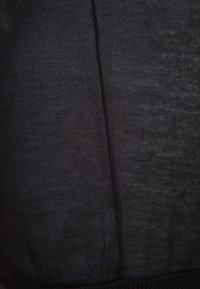 Tela de color gris oscuro con una costura vertical central y una textura sutil, mostrando un material de punto fino y una ligera variación de color.