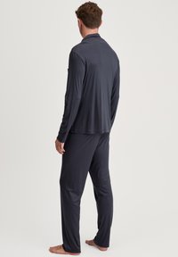 Donkergrijze lange mouwen top en bijpassende broek van zachte stof. Het ontwerp heeft een eenvoudige kraag en een relaxte pasvorm.