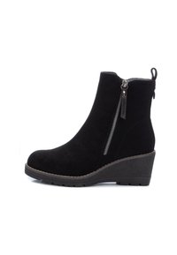 Botas de tobillo de ante negro con tacón de cuña, cierre de cremallera lateral y suela texturizada. Cuenta con una pestaña de lazo para facilitar su uso.