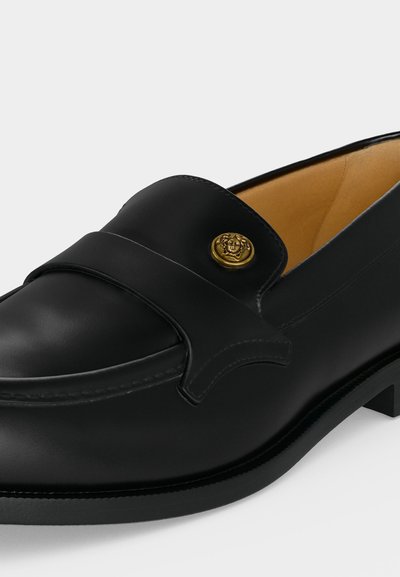 Μαύρο δερμάτινο loafers με χρυσό διακοσμητικό κουμπί και χαμηλό τακούνι, με λείο ταμπά εσωτερικό φόδρα.
