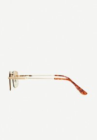 Rám z kovu zlatého tónu s priehľadnými sklami a pažami s korytnačím vzorom. Obsahuje dekoratívne detaily na mostíku a rámikoch.