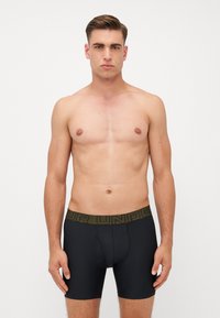 Men's black boxer briefs with a snug fit, made from stretchy material. Features a wide, textured waistband in olive green with "YOUR UNDER…" printed.