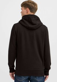 Sudadera negra con capucha hecha de tela suave, que cuenta con mangas largas y un bolsillo canguro, con puños y dobladillo acanalados.