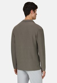 Geripptes Langarmshirt in gedämpftem Olivgrün, mit Kragen und glatter Textur. Maßgeschneiderte Passform mit geradem Saum.