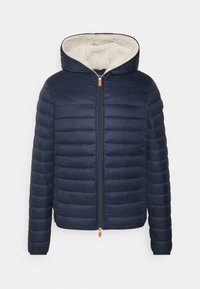 Marinblå vadderad jacka med dragkedja framtill, med en krämfärgad fuskpälsfoder i huvan, elastiska mudd, och en orange dragkedjedetalj.