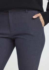 Navy blue tailored trousers with a smooth texture, straight cut, and side pockets. Fabric has a subtle weave pattern.