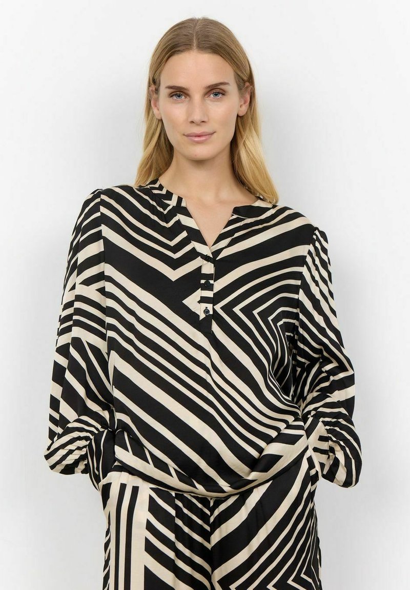 Zwart en beige langemouwen shirt met contrasterende zigzagpatronen, een V-hals en knoopsluiting, gemaakt van een soepele, lichtgewicht stof.