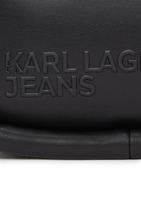 Borsa in pelle nera con texture, caratterizzata dal logo goffrato "KARL LAGERFELD JEANS". Manico liscio e arrotondato e design minimalista.