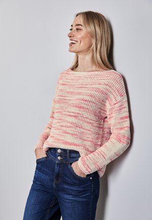 Pull en tricot avec des rayures rose pastel et crème, col rond et texture côtelée, associé à un jean taille haute bleu foncé.