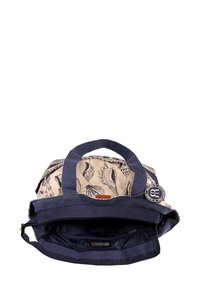 Sac en toile avec des poignées bleu foncé, présentant une doublure intérieure beige clair imprimée de coquillages. Comprend une poche zippée et une étiquette de logo.