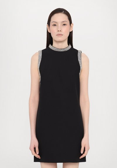 Robe noire sans manches, avec un col montant et des bordures argentées ornées aux épaules. Le tissu semble lisse avec un design structuré.