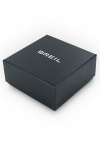 Caja de cartón negra con un acabado mate, con el texto en relieve blanco "BREIL" en la parte superior. Forma cuadrada con bordes limpios.