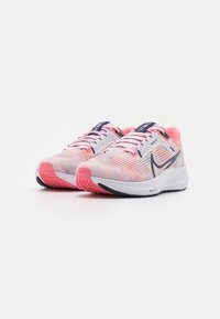 Zapatillas de running con parte superior de malla ligera en rosa y blanco, con detalles en azul marino, suela texturizada y motas multicolores.