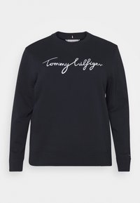 Zwarte sweatshirt van katoen met een ronde hals en lange mouwen. "Tommy Hilfiger" is in witte cursieve letters op de borst geborduurd.