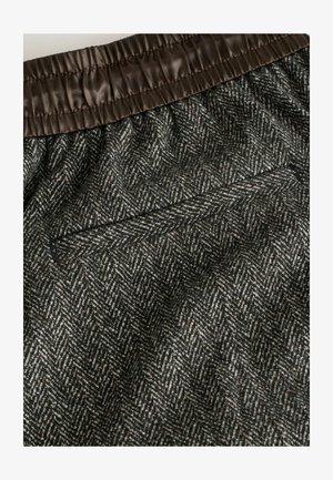 Woven fabric shorts featuring a herringbone pattern in dark gray and beige, with a brown elastic waistband and a discreet back pocket.
