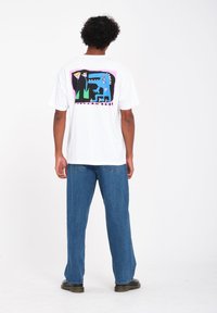 Witte katoenen t-shirt met een kleurraf grafiek op de achterkant, met abstracte vormen, waaronder een blauw creature en groene accenten. Casual pasvorm.