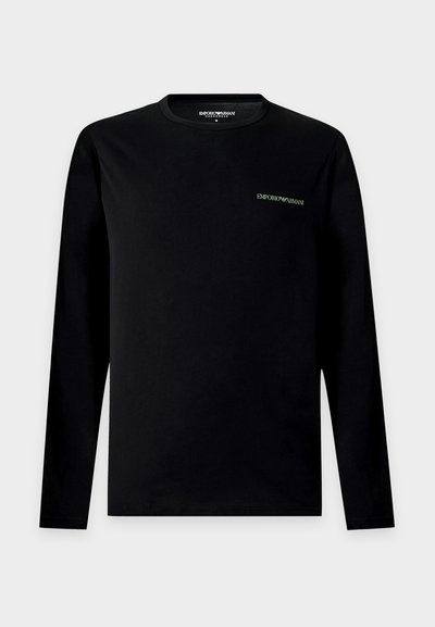 Μαύρο μακρυμάνικο πουκάμισο Emporio Armani με μικρό λευκό λογότυπο στο αριστερό μέρος του στήθους, στρογγυλή λαιμόκοψη και απλό σχέδιο σε ανοιχτό γκρι φόντο.