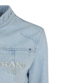 Svijetloplavi traper jakna s visokim ovratnikom, prednjim džepom i izvezenim logom "KANI". Sadrži mali detalj u obliku srca.