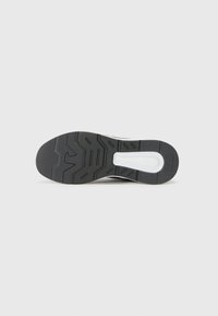 Black rubber shoe sole with textured patterns and a white midsole. Features a distinctive logo and grooves for traction.