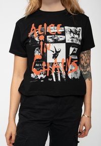 Black cotton t-shirt featuring a collage print with white and orange graphics, including "Alice in Chains" text and various black-and-white images.