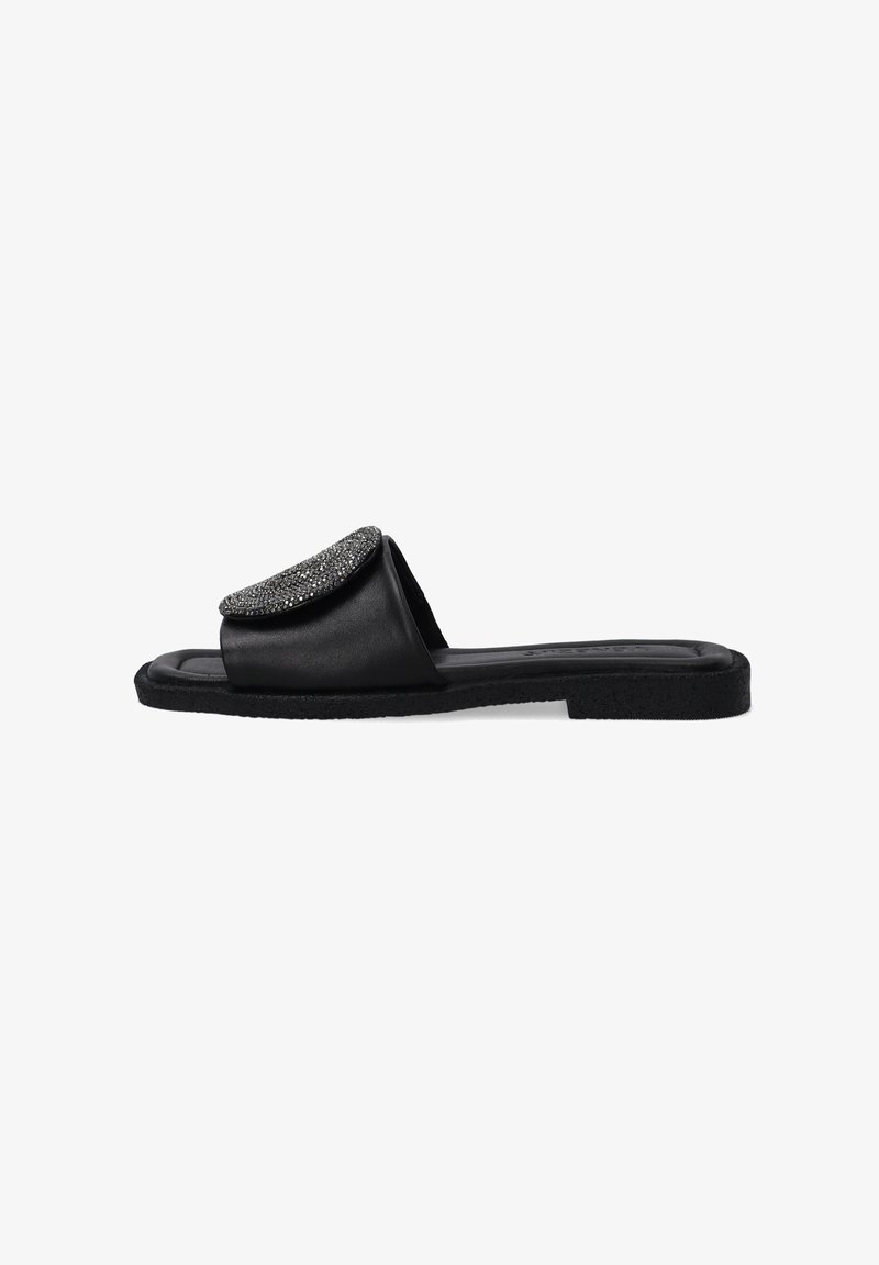 Black flat slide sandal with a textured strap featuring a round, embellished detail. Soft material with a flat, rubber sole.