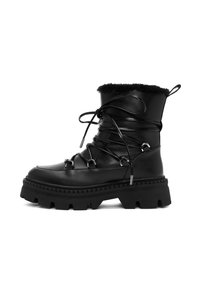 Bota de combate de cuero negro con puntera redondeada, suela gruesa con dibujo, forro de piel de animal y cordones decorativos con acentos de metal.