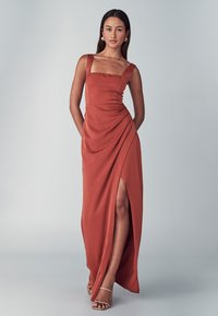 Kupferfarbene Maxikleid mit quadratischem Ausschnitt, drapiertem Design und einem hohen Schlitz bis zum Oberschenkel. Hergestellt aus glattem Stoff mit dünnen Schulterträgern.