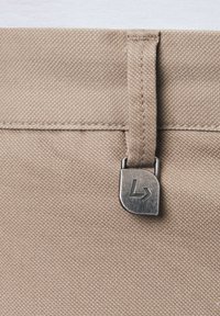 Beżowy materiałowy pas z teksturowaną powierzchnią, z metalowym zapięciem z logo i schludnym przeszyciem wzdłuż górnej krawędzi.