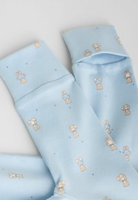 Șosete bleu deschise confecționate din țesătură moale, cu modele mici și repetate de iepurași bej cu dungi albastre; manșetele sunt albastre uni.