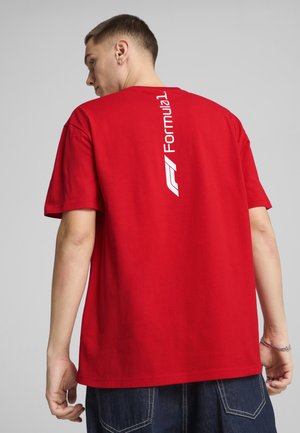 Red cotton t-shirt featuring a white "Formula 1" logo printed vertically on the back. Short sleeves and a relaxed fit.