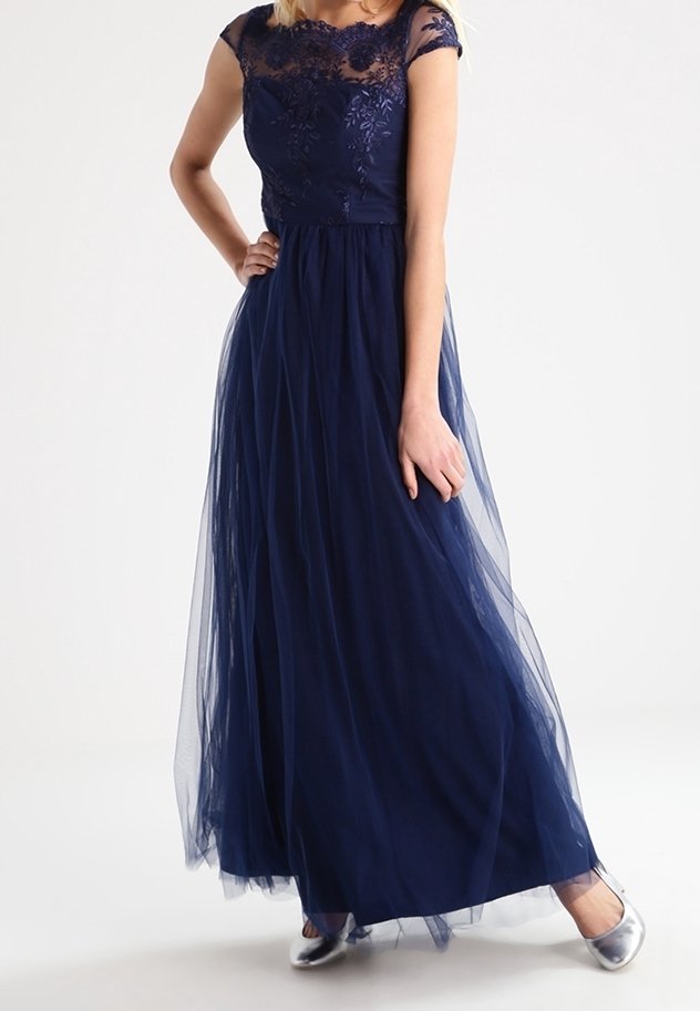 Abito da sera blu navy con bodice in pizzo floreale, maniche a cappuccio e gonna in tulle a strati, abbinato a scarpe piatte argentate.
