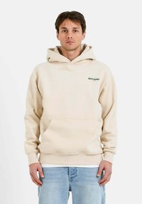 Sudadera con capucha beige, con bolsillo tipo canguro, puños y dobladillo acanalados; presenta un logo de texto verde en el área del lado izquierdo del pecho.