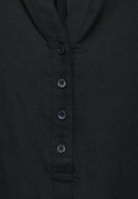 Czarna koszula z guzikami, wykonana z miękkiego materiału, z dekoltem w kształcie V oraz sześcioma okrągłymi, ciemnymi guzikami z przodu.