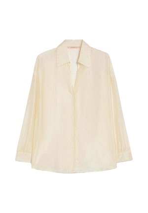 Blusa beige chiaro a maniche lunghe con piccoli puntini neri, chiusura con bottoni sul davanti e ampio colletto appuntito.