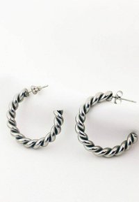 Orecchini a cerchio in tonalità argento tortili con una finitura lucida, dotati di chiusura a perno e di forma cilindrica e circolare.